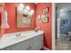 Bathroom with vibrant coral walls, framed art, and a white vanity with a sink and decorative mirror at 3932 Rounding Run Rd, Charlotte, NC 28277