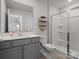 Well-lit bathroom featuring a gray vanity, toilet, shelving, and a glass-enclosed shower at 5581 Soft Shell Dr, Lancaster, SC 29720