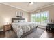Cozy bedroom featuring a large bed, ceiling fan and natural light from shuttered windows at 6010 Albiza Dr, Harrisburg, NC 28075