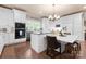 Bright kitchen boasts white cabinetry, stainless appliances, an island with seating, and hardwood flooring at 6010 Albiza Dr, Harrisburg, NC 28075