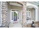Inviting front porch with stone pillars, a welcome mat, and a decorative wreath on the glass front door at 6021 Piscataway Ct, Rock Hill, SC 29732