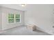 Bedroom with neutral walls features a window, plush carpet, and a wooden chest at 6171 Willow Farm Dr, Denver, NC 28037