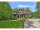 Beautiful two-story home with stone accents, lush landscaping, and a winding driveway leading to a three-car garage at 6171 Willow Farm Dr, Denver, NC 28037