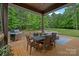 Covered deck showcasing an outdoor dining area with grill and ample seating, perfect for enjoying the wooded scenery at 6171 Willow Farm Dr, Denver, NC 28037