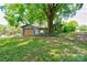 Exterior view of a shed with a wood door and gray siding, surrounded by lush trees and lawn at 619 E Sanders Rd, Shelby, NC 28150