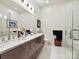 Bright modern bathroom with double vanity, marble countertops, and a glass-enclosed shower at 6309 Wakehurst Rd, Charlotte, NC 28226