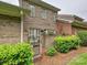 View of brick townhouse exterior and gated garden area, surrounded by lush greenery and mature trees at 6309 Wakehurst Rd, Charlotte, NC 28226