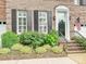 Close-up of brick front entrance, lush landscaping, and black shutters enhancing curb appeal at 6309 Wakehurst Rd, Charlotte, NC 28226