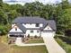 An aerial view showcasing a modern farmhouse with a large lot surrounded by lush trees at 685 Knollcrest Ne Dr, Concord, NC 28025