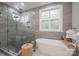 Modern bathroom featuring gray tile, a glass-enclosed shower, and a soaking tub by a window at 685 Knollcrest Ne Dr, Concord, NC 28025