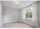 Bright bedroom with light wood floors, large window with white curtains, and white door at 685 Knollcrest Ne Dr, Concord, NC 28025