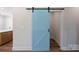 Hallway features a sky-blue sliding barn door that adds color to the neutral walls and wood-look floors at 7426 Hambright Rd, Huntersville, NC 28078