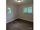 A sunlit bedroom featuring dark wood floors and two windows, bringing in natural light and views at 1002 Hemlock Dr, Shelby, NC 28150