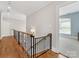 Upstairs hallway with wood floors, iron railing, and view to secondary bedroom at 1200 Firethorne Club Dr, Marvin, NC 28173