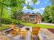 Expansive brick home backyard featuring a stone fire pit, mature trees and a screened porch at 1200 Firethorne Club Dr, Waxhaw, NC 28173