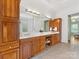 Bathroom featuring double vanity with wood cabinetry, dual sinks and a glass block wall at 1200 Firethorne Club Dr, Waxhaw, NC 28173