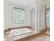 Bathroom with a white jetted tub, tiled platform, and glass block window at 1200 Firethorne Club Dr, Waxhaw, NC 28173