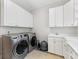 Bright laundry room with white cabinets, tan tile flooring and modern washer and dryer at 1200 Firethorne Club Dr, Waxhaw, NC 28173