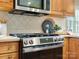 Close-up of a stainless steel gas range with microwave and tile backsplash at 12632 Landing Green Dr, Charlotte, NC 28277