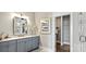 Bathroom vanity with gray cabinets, white countertop, square mirror, decorative vases, and walk-in closet access at 13241 Cozy Ct, Charlotte, NC 28215