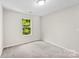Bright bedroom features a window with a view of lush greenery and neutral carpeting at 1411 Duhart Ave, Gastonia, NC 28054