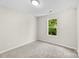 This bedroom features neutral paint and carpet with a window view of trees at 1411 Duhart Ave, Gastonia, NC 28054