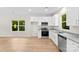 Kitchen showcasing stainless steel appliances, white cabinets, granite countertops, hardwood floors, and a sunny window view at 1411 Duhart Ave, Gastonia, NC 28054