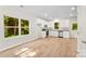 Open-concept living room featuring wood-look floors, white walls, and windows overlooking greenery at 1411 Duhart Ave, Gastonia, NC 28054