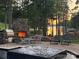 Inviting outdoor stone fireplace and jacuzzi at sunset with lake views, perfect for relaxing and entertaining outdoors at 143 Jeremy Point Pl, Mooresville, NC 28117