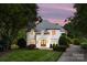Elegant home featuring an arched entryway, meticulous landscaping, and a gray shingle roof set against a pastel sunset at 15038 Jockeys Ridge Dr, Charlotte, NC 28277