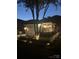 Charming backyard at twilight featuring a well-lit patio, white picket fence, and lush landscaping at 17130 Bridgeton Ln, Huntersville, NC 28078