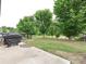 View of backyard with lush lawn, trees and a barbecue grill at 1769 Evergreen Dr, Charlotte, NC 28208