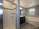 Bathroom featuring a glass-enclosed shower, soaking tub and a dark vanity with a window at 1769 Evergreen Dr, Charlotte, NC 28208