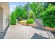 Beautiful stone patio with lush greenery, a wooden retaining wall, and steps leading to the landscaped yard at 204 Aztec Cir, Mooresville, NC 28117