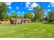 A well-kept brick home on a large green lawn beneath a bright sky and lush trees at 245 Kingsway Cir, Charlotte, NC 28214