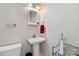 A tidy half-bathroom exhibits a white pedestal sink, a red hand towel, and a round toilet at 4960 York Hwy, Rock Hill, SC 29732