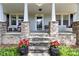 Close-up of a charming front porch with a sitting area, stone pillars, and red potted flowers at 4960 York Hwy, Rock Hill, SC 29732