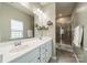 Bathroom with double sinks, large mirror, shower, neutral paint, and decorative shelves at 509 Silers Bald Dr, Fort Mill, SC 29715