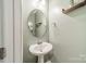 Charming powder room with a pedestal sink, a round mirror, and neutral paint at 509 Silers Bald Dr, Fort Mill, SC 29715
