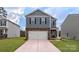 New two-story home boasts gray siding, stone accents, a two-car garage, and a well-manicured lawn at 581 E Sparkleberry St, Chester, SC 29706
