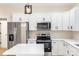 Close-up of a kitchen with stainless steel appliances, white cabinets, and a center island at 605 Stirewalt Rd, China Grove, NC 28023