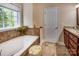 Bright bathroom with a garden tub under a window, granite countertops, and tile floors at 7245 Willow Brook Ct, Denver, NC 28037