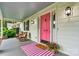 Inviting front porch with rocking chairs, a colorful rug, flowers, and a charming pink front door at 8218 Bright Water Ln, Denver, NC 28037