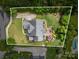 An aerial view of a landscaped backyard with an outdoor seating area, bordered by mature trees and lush greenery at 8962 Landsdowne Ave, Harrisburg, NC 28075