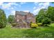 Beautiful backyard view featuring lush green grass, a stone fireplace, and mature trees, perfect for outdoor enjoyment at 8962 Landsdowne Ave, Harrisburg, NC 28075