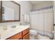 Well-lit bathroom features a wood vanity, a toilet, and a shower with a patterned curtain at 8962 Landsdowne Ave, Harrisburg, NC 28075