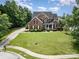 Traditional brick home featuring a manicured lawn, mature trees, and a winding driveway at 8962 Landsdowne Ave, Harrisburg, NC 28075