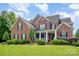 Charming two-story brick home with a manicured lawn and inviting front porch with white pillars at 8962 Landsdowne Ave, Harrisburg, NC 28075