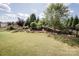 Backyard with expansive lawn, landscaped gardens, and a decorative stone retaining wall at 9026 Raven Top Dr, Mint Hill, NC 28227