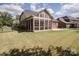 Backyard view of brick home with a screened-in porch and lush green lawn at 9026 Raven Top Dr, Mint Hill, NC 28227